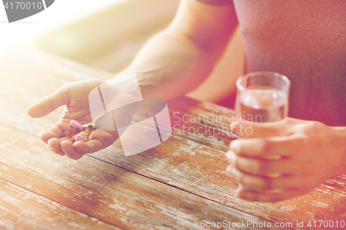 Image of close up of male hands holding pills and water