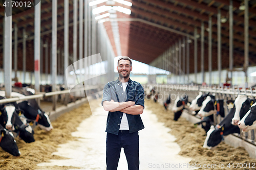 Image of man or farmer with cows in cowshed on dairy farm