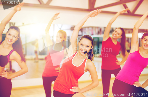 Image of group of smiling people stretching in the gym