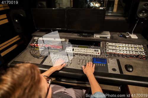 Image of man at mixing console in music recording studio