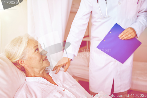 Image of doctor visiting happy senior woman at hospital