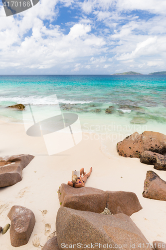 Image of Woman reading book on picture perfect beach Anse Patates on La Digue Island, Seychelles.