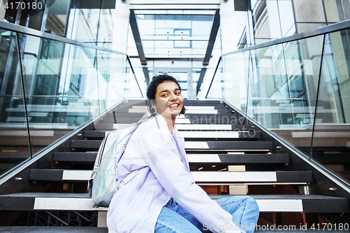 Image of young cute indian girl at university building sitting on stairs 