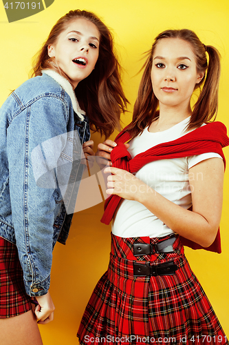 Image of lifestyle people concept: two pretty school girl having fun on yellow background, happy smiling students