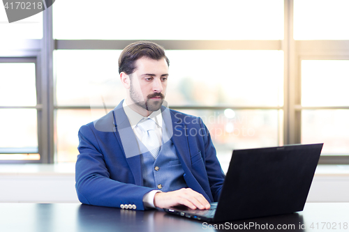 Image of Businessman in office working on laptop computer.