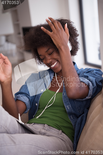 Image of African american woman at home in chair with tablet and head pho