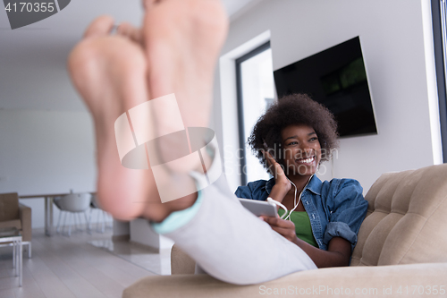 Image of African american woman at home in chair with tablet and head pho