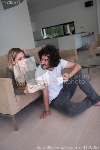 Image of couple relaxing at  home with tablet computers