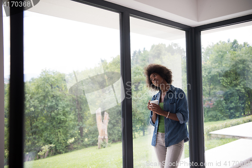 Image of African American woman drinking coffee looking out the window