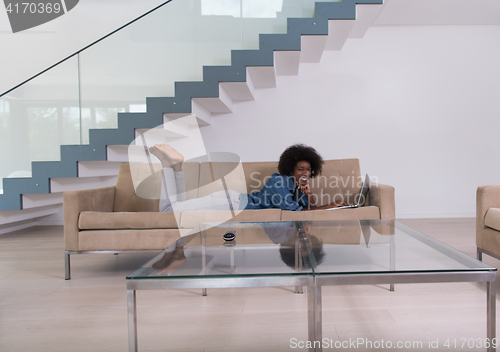 Image of African American woman using laptop on sofa