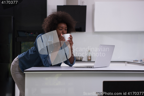 Image of smiling black woman in modern kitchen