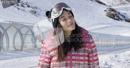 Image of Young woman relaxing on ski slope in winter