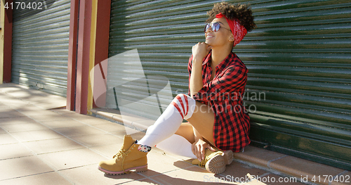 Image of Gorgeous african american girl sitting next to fence