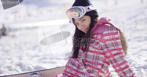 Image of Beautiful asian snowboarder sitting on snow