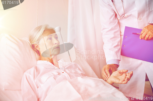 Image of doctor checking senior woman pulse at hospital