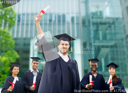 Image of happy students in mortar boards with diplomas