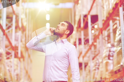 Image of serious man calling on smartphone at warehouse