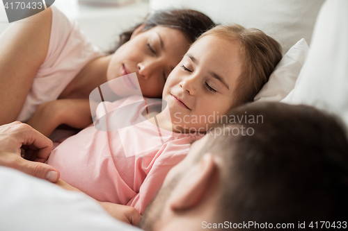 Image of happy family sleeping in bed at home