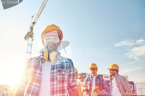 Image of group of smiling builders in hardhats outdoors