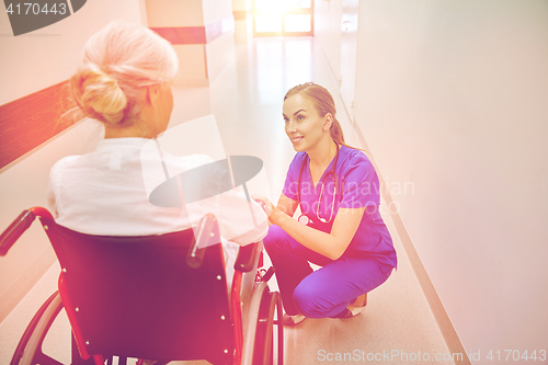 Image of nurse with senior woman in wheelchair at hospital