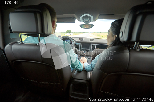 Image of happy couple driving in car and holding hands