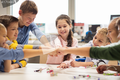 Image of happy children making fist bump at robotics school