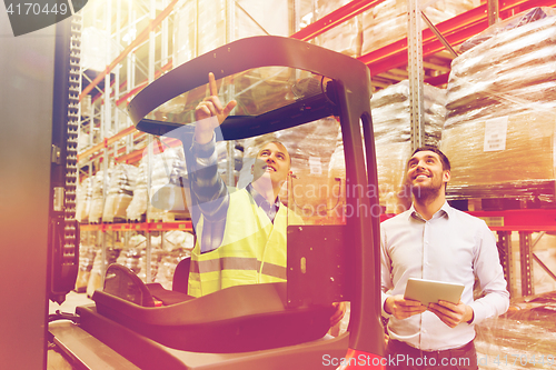 Image of men with tablet pc and forklift at warehouse