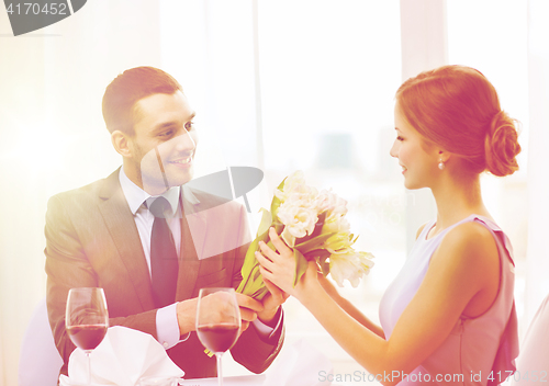 Image of smiling man giving flower bouquet at restaurant