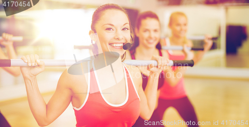 Image of group of smiling people working out with barbells