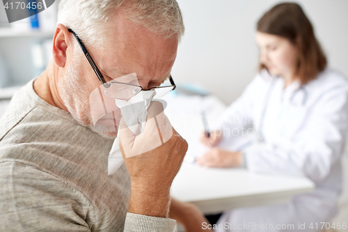 Image of senior man blowing nose and doctor at hospital