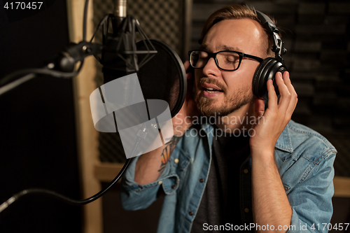 Image of man with headphones singing at recording studio