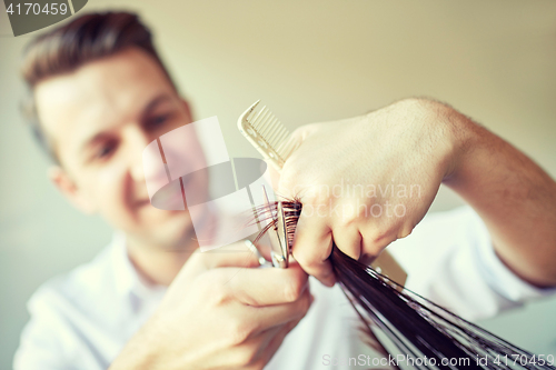 Image of stylist with scissors cutting hair tips at salon