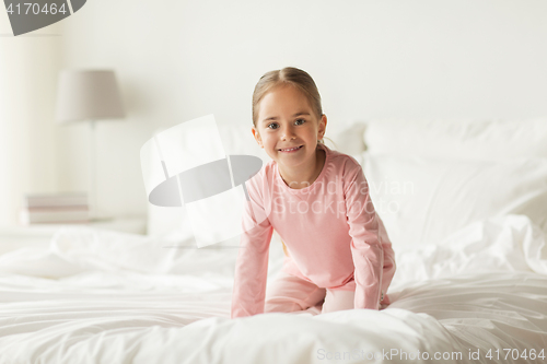 Image of happy little girl on bed at home bedroom