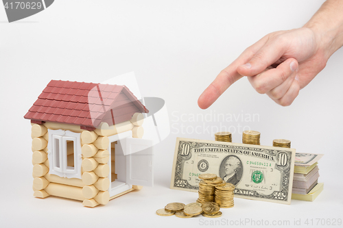 Image of Toy house, lie near the money to buy, hand on top shows a finger