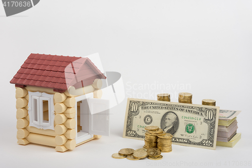 Image of Toy house near the money is to purchase a pack of bills and a stack of coins