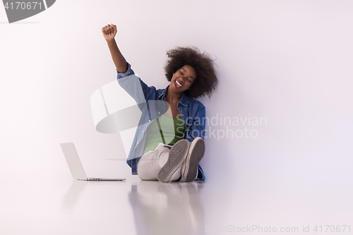 Image of african american woman sitting on floor with laptop