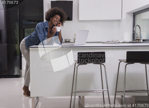 Image of smiling black woman in modern kitchen