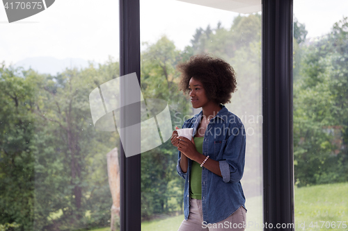 Image of African American woman drinking coffee looking out the window