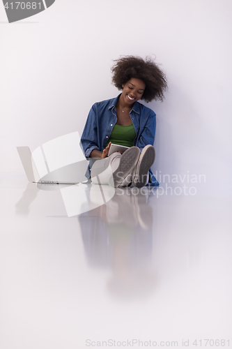 Image of african american woman sitting on floor with laptop