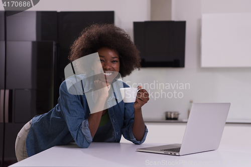 Image of smiling black woman in modern kitchen