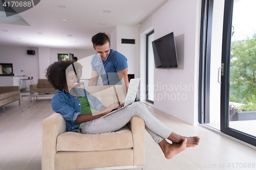 Image of multiethnic couple on an armchair with a laptop
