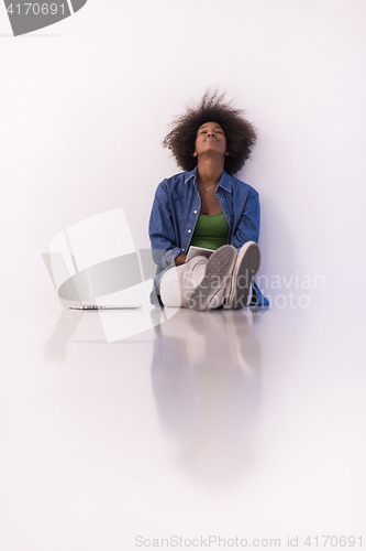 Image of african american woman sitting on floor with laptop