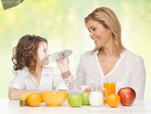 Image of happy mother and daughter eating healthy breakfast