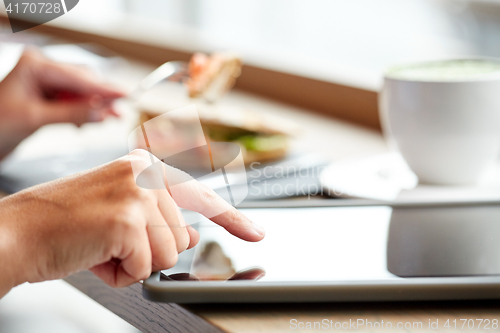 Image of woman with tablet pc and panini sandwich at cafe