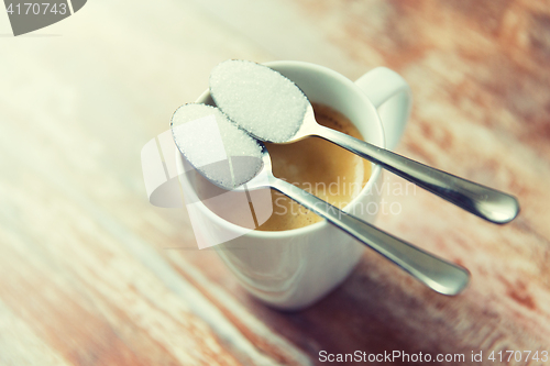 Image of close up of white sugar on teaspoon and coffee cup