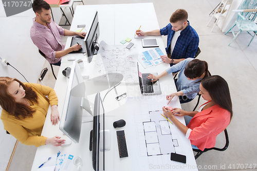 Image of creative team with computers, blueprint at office