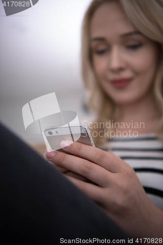 Image of woman sitting on sofa with mobile phone