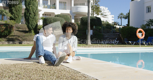 Image of Young couple relaxing alongside an urban pool