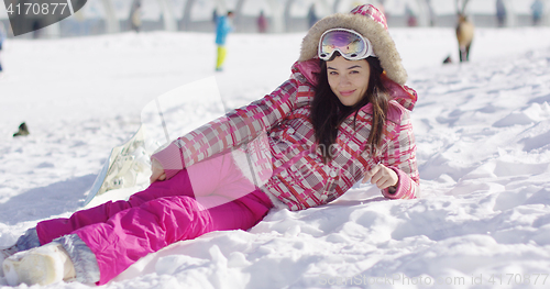 Image of Young woman in pink snowsuit with ski goggles