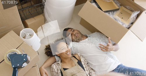 Image of Attractive couple lying on the floor of their home